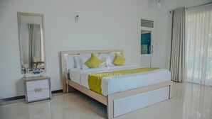 Una habitación de hotel con cama, mesita de noche, espejo y ventana con cortinas.