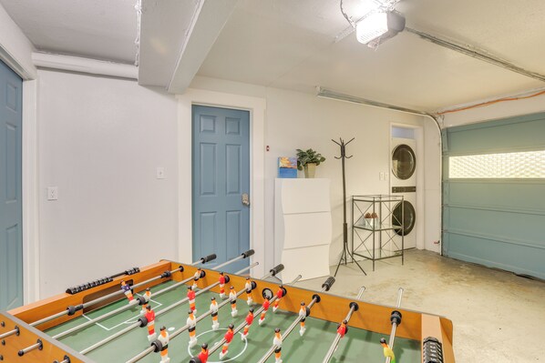 A room with a foosball table, a blue door, a coat rack, and a washing machine. - 7 Mi to Dtwn: Family-Friendly Abode in Seattle! (Seattle)