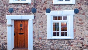 A stone building with a wooden door and two windows with white frames. - Historic Cottage & Garden nr Quantock Hills (Nether Stowey)