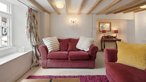A living room with a red sofa, a yellow throw, and a wooden coffee table.