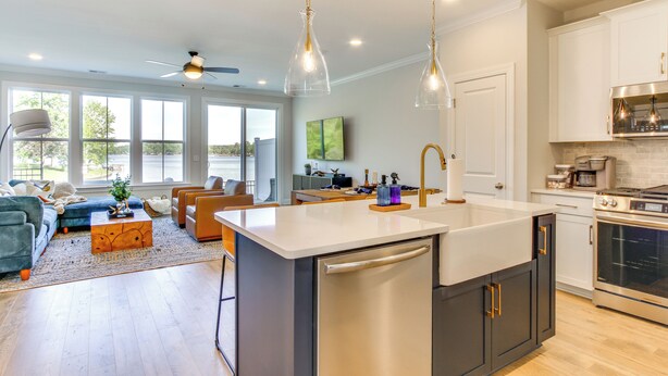 Una cocina moderna con una isla central, electrodomésticos de acero inoxidable e iluminación colgante.