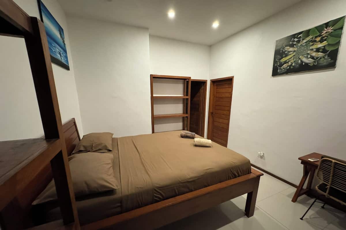 A bedroom with a wooden bed, a wardrobe, a small table, and a chair.