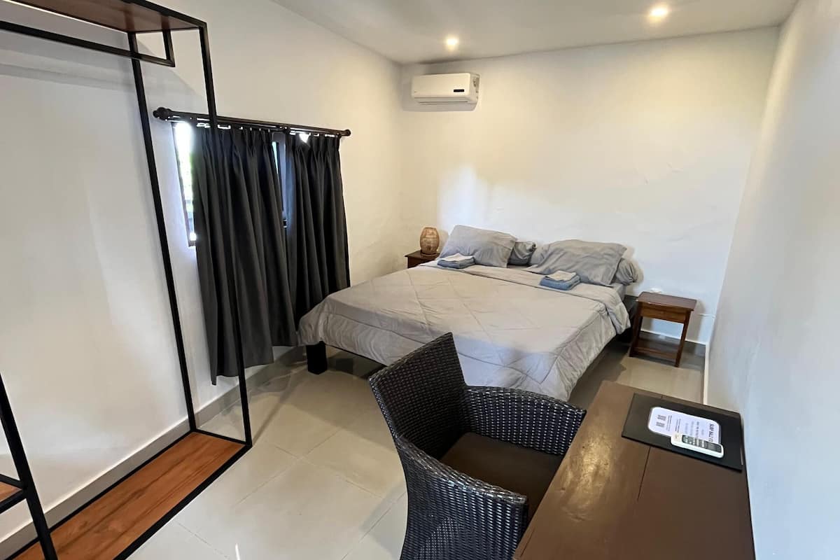 A hotel room with a bed, a desk, a chair, and a wardrobe.