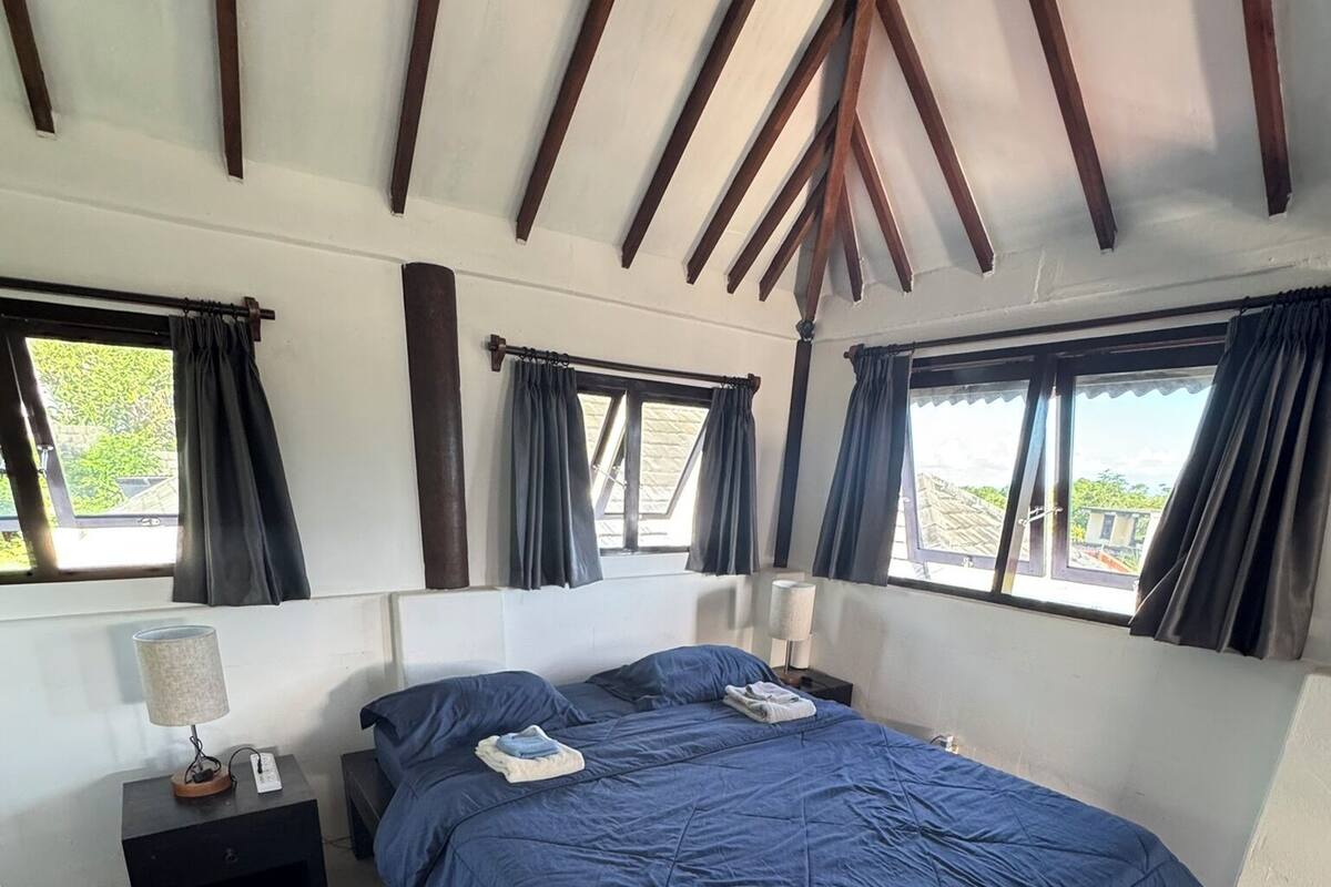 A bedroom with a large bed, two bedside tables, and a window with curtains.