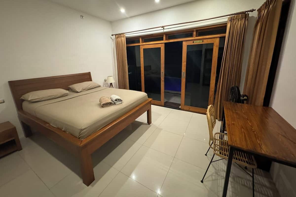 A bedroom with a wooden bed, a small table, and a chair.