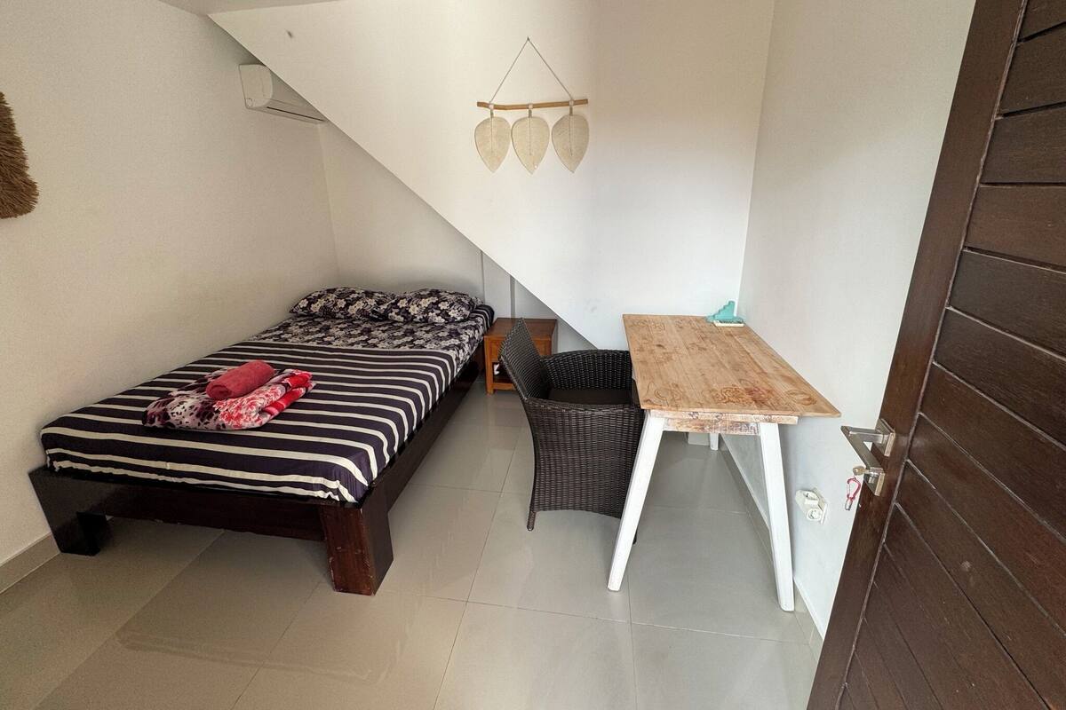 A compact room with a bed, a small table, and a chair.