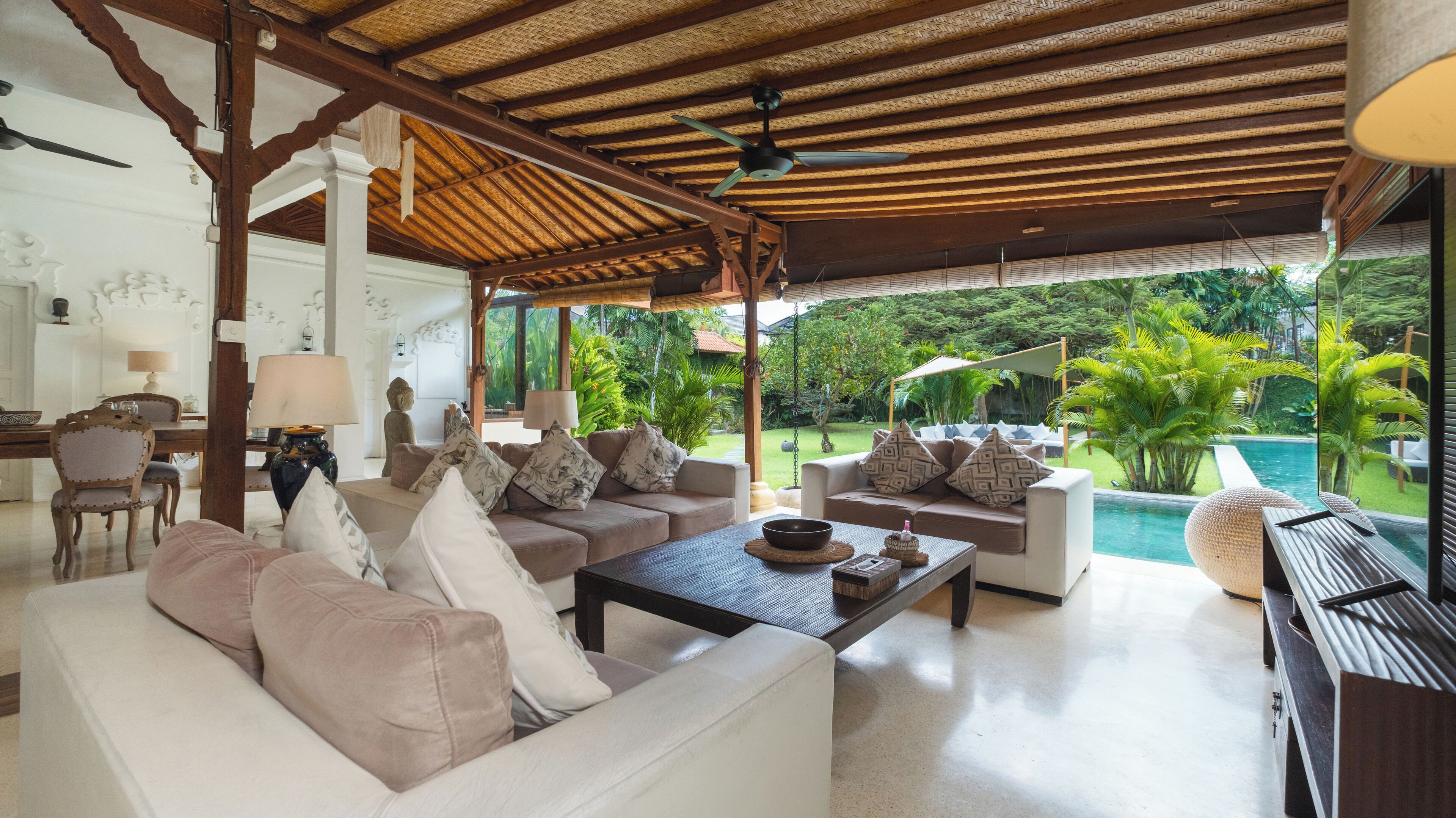 A spacious living area with a pool view, featuring sofas, a coffee table, and a dining area.