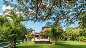 Ein tropisches Resort mit Schwimmbad, Außenbereich und üppiger Vegetation.