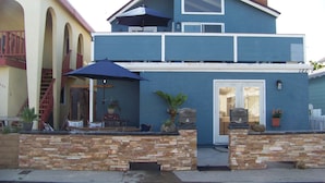 A two-story house with a stone wall in front, a blue exterior, and a front door.