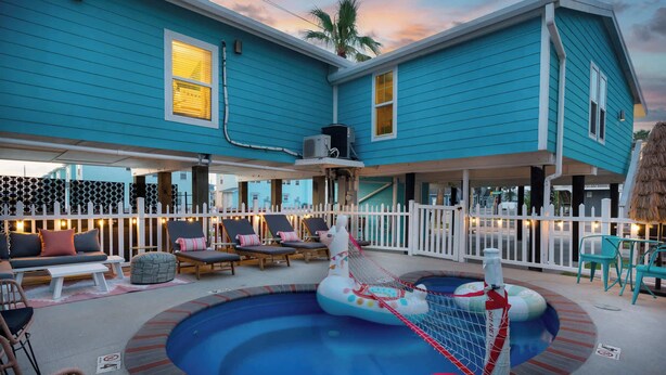 Un espace piscine doté d’une structure de jeux flottante, de chaises longues et d’un coin salon couvert offrant une vue sur la piscine.