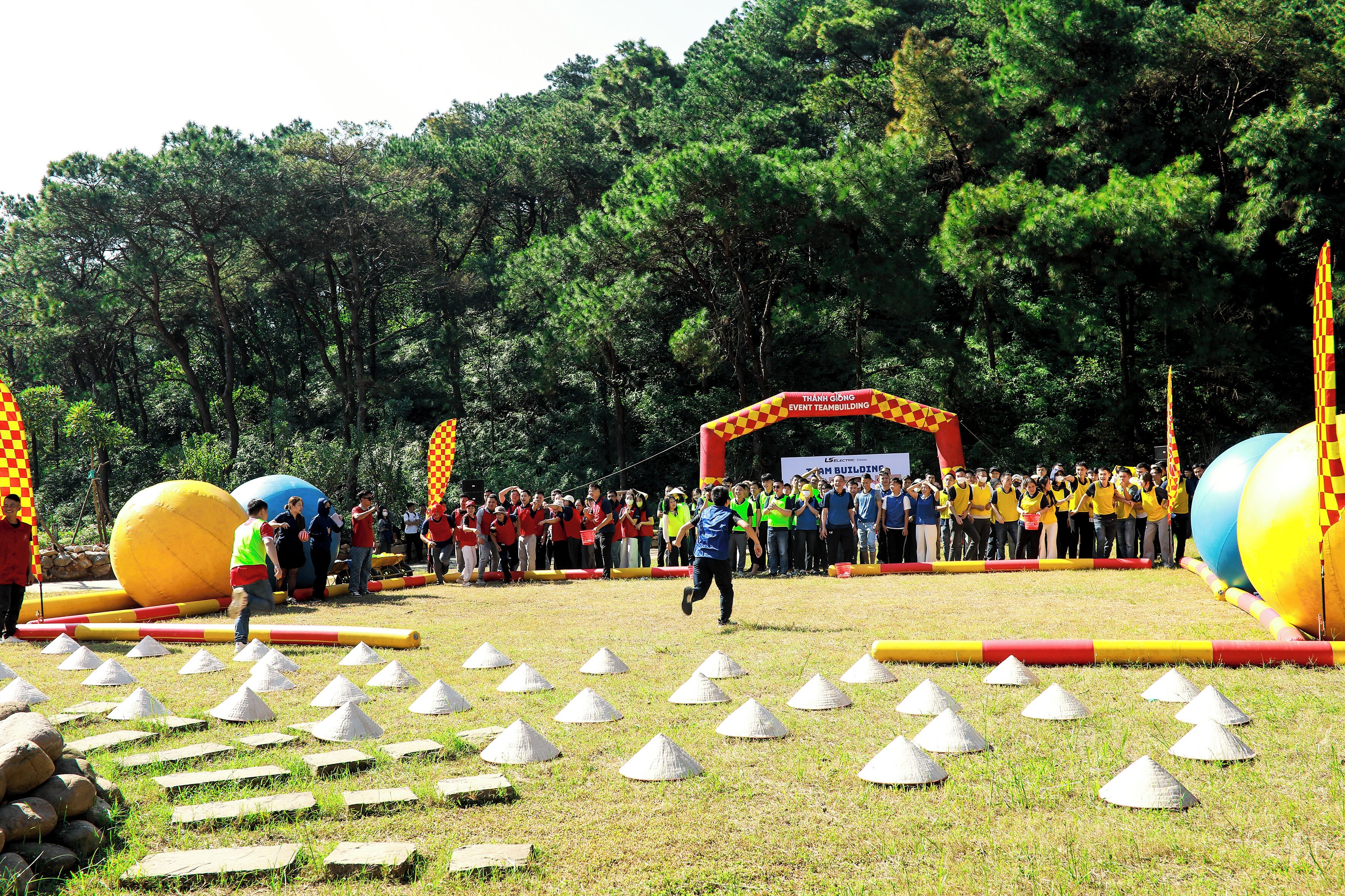 An outdoor event with a crowd, a large inflatable ball, and a checkered archway.