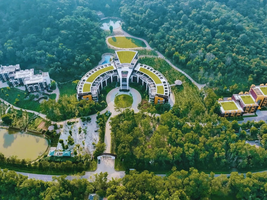 An aerial view of a modern hotel complex with multiple buildings, a central courtyard, and surrounding greenery.