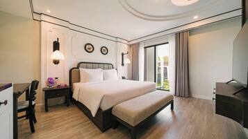 A modern hotel room with a large bed, bedside tables, a desk, and a TV.