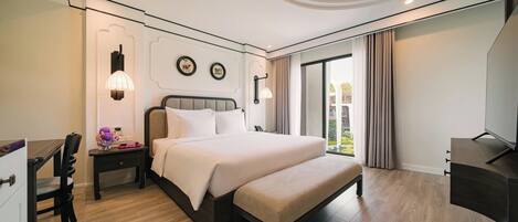 A modern hotel room with a large bed, bedside tables, a desk, and a TV.