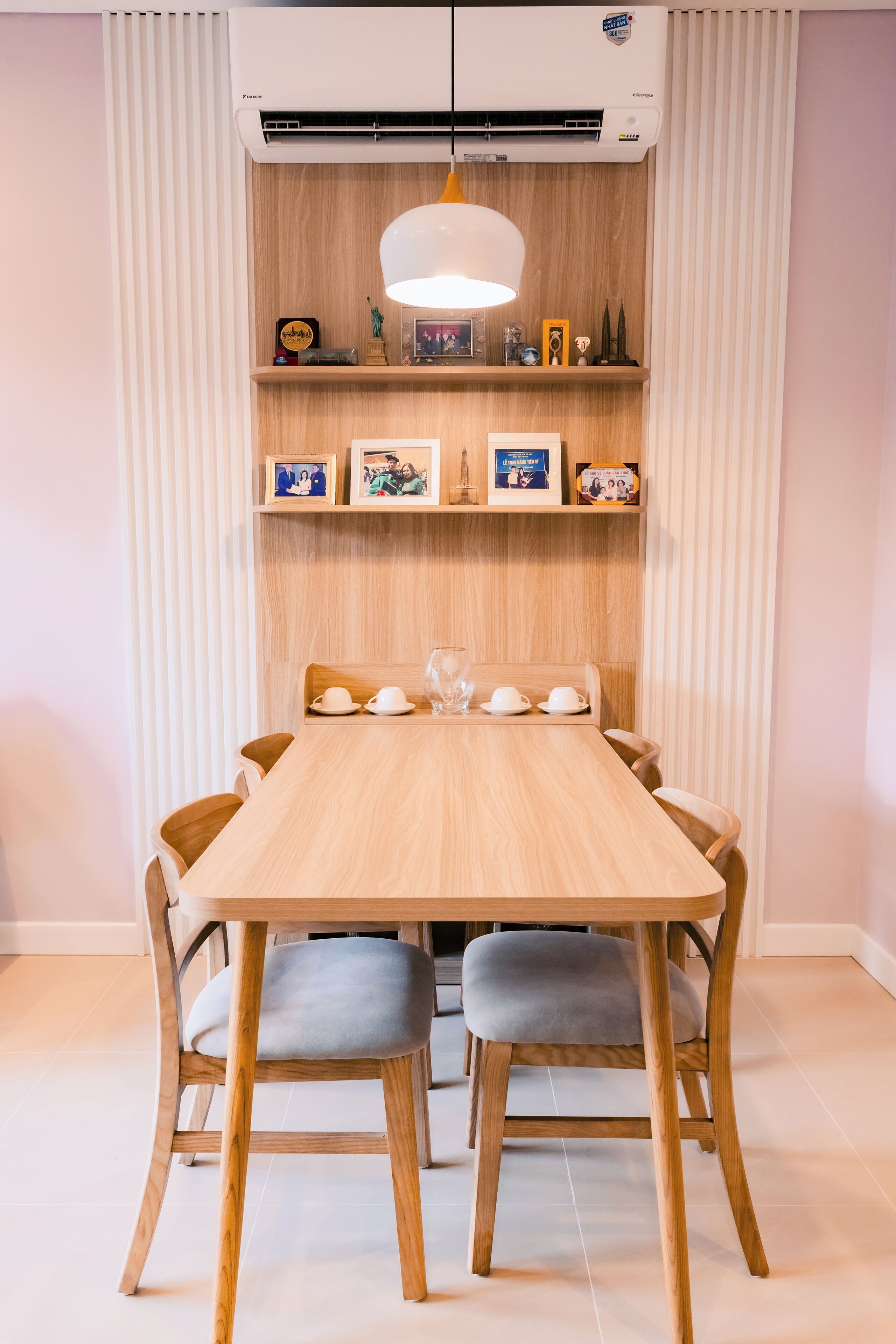A dining area with a wooden table, grey upholstered chairs, and a pendant light.