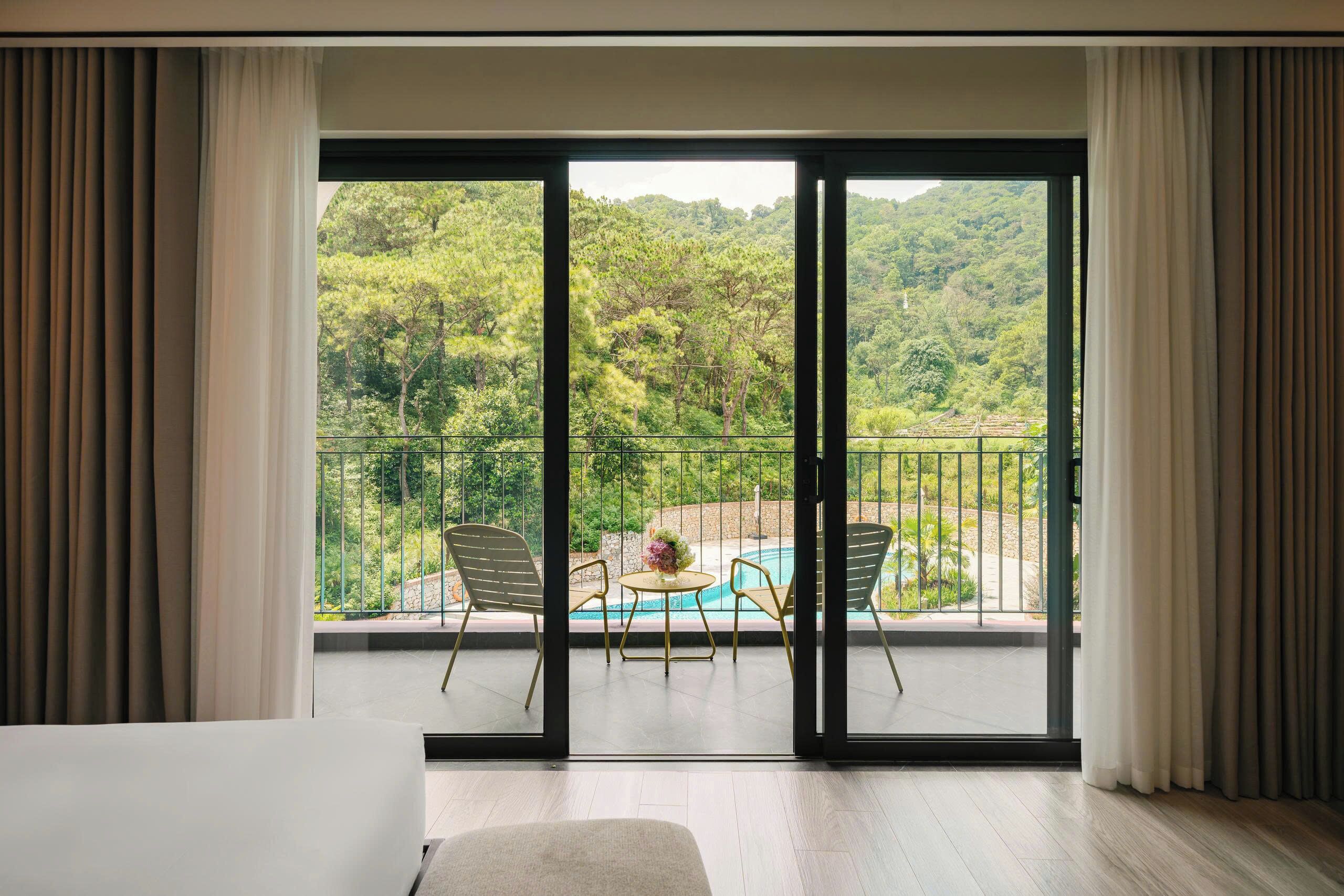 Ein Zimmer mit einer großen Schiebeglasdoor, die auf einen Balkon mit Pool und Sitzgelegenheiten führt.