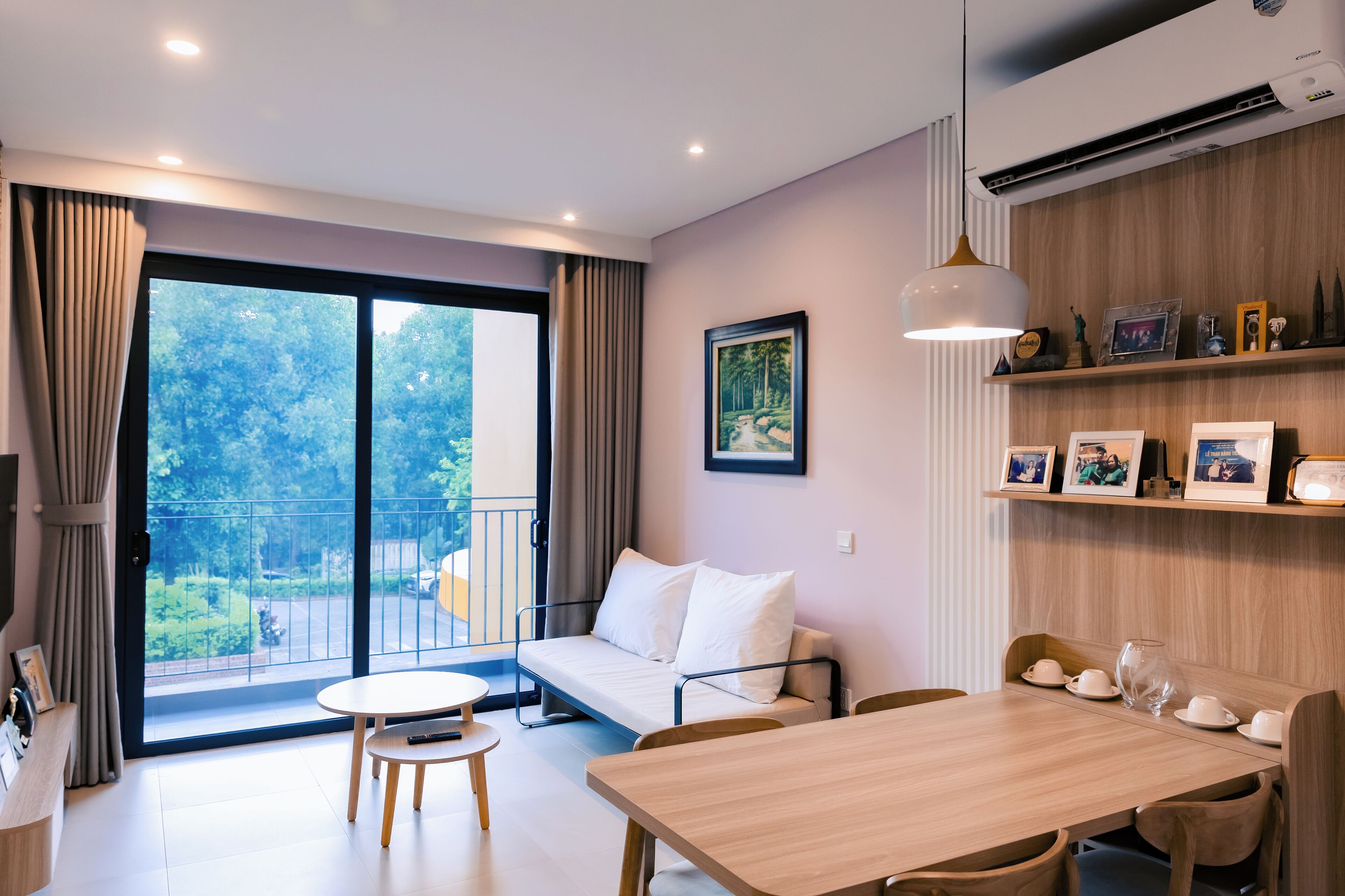 Una habitación moderna con sofá, una mesa de comedor y un balcón con vistas a la vegetación.