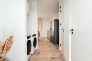 Ein Waschraum mit zwei Waschmaschinen und einem großen Kühlschrank.