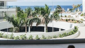 Un bâtiment moderne doté d’une piscine, de palmiers et offrant une vue sur l’océan.