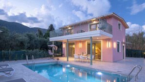 A two-story house with a swimming pool, outdoor furniture, and a balcony.