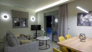 A modern living room with a grey sofa, a round coffee table, a TV, and a dining table with yellow chairs.