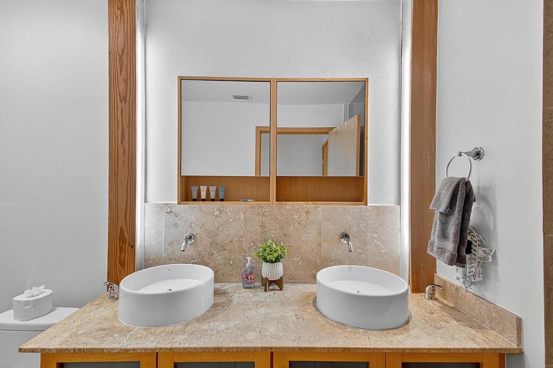 Un baño con dos lavamanos, un espejo y un perchero para toallas.