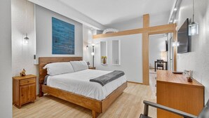 Een moderne slaapkamer met een houten bed, nachtkastjes, een bureau en een televisie.