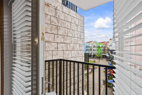 A balcony with a stone wall, a metal railing, and a view of colorful buildings in the background.