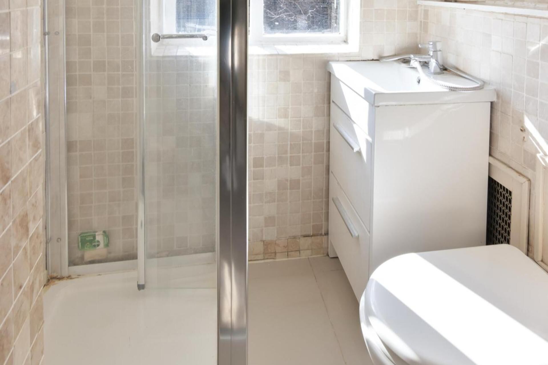 A bathroom with a glass shower door, a white sink, and a toilet.