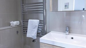 A modern bathroom with a white sink, a towel rack, and a shower. - 2-bed Gucci Flat - Sleeps 6 & Close to Harrods (London)