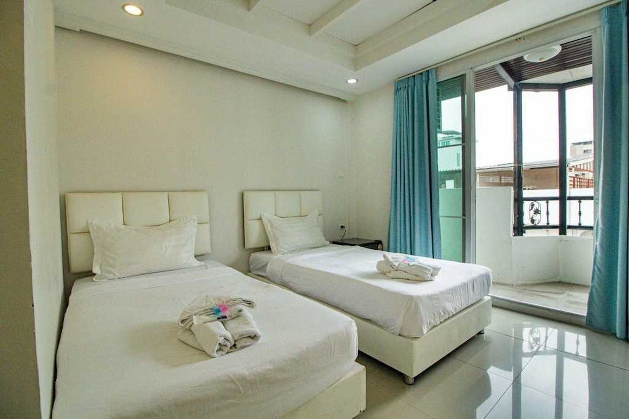 A hotel room with two beds, a window with curtains, and a balcony.