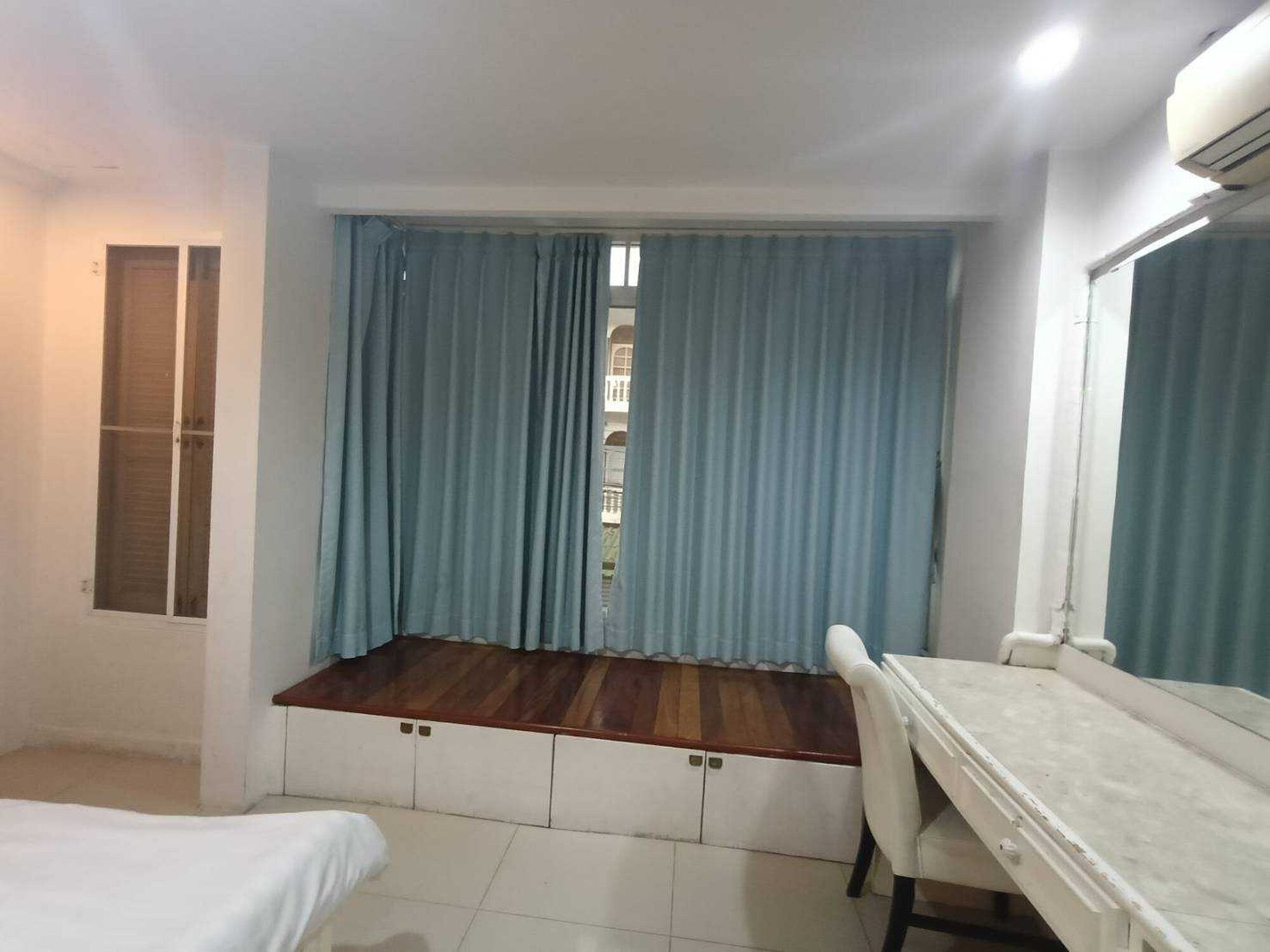 A room with a bed, a desk, and a window with curtains.