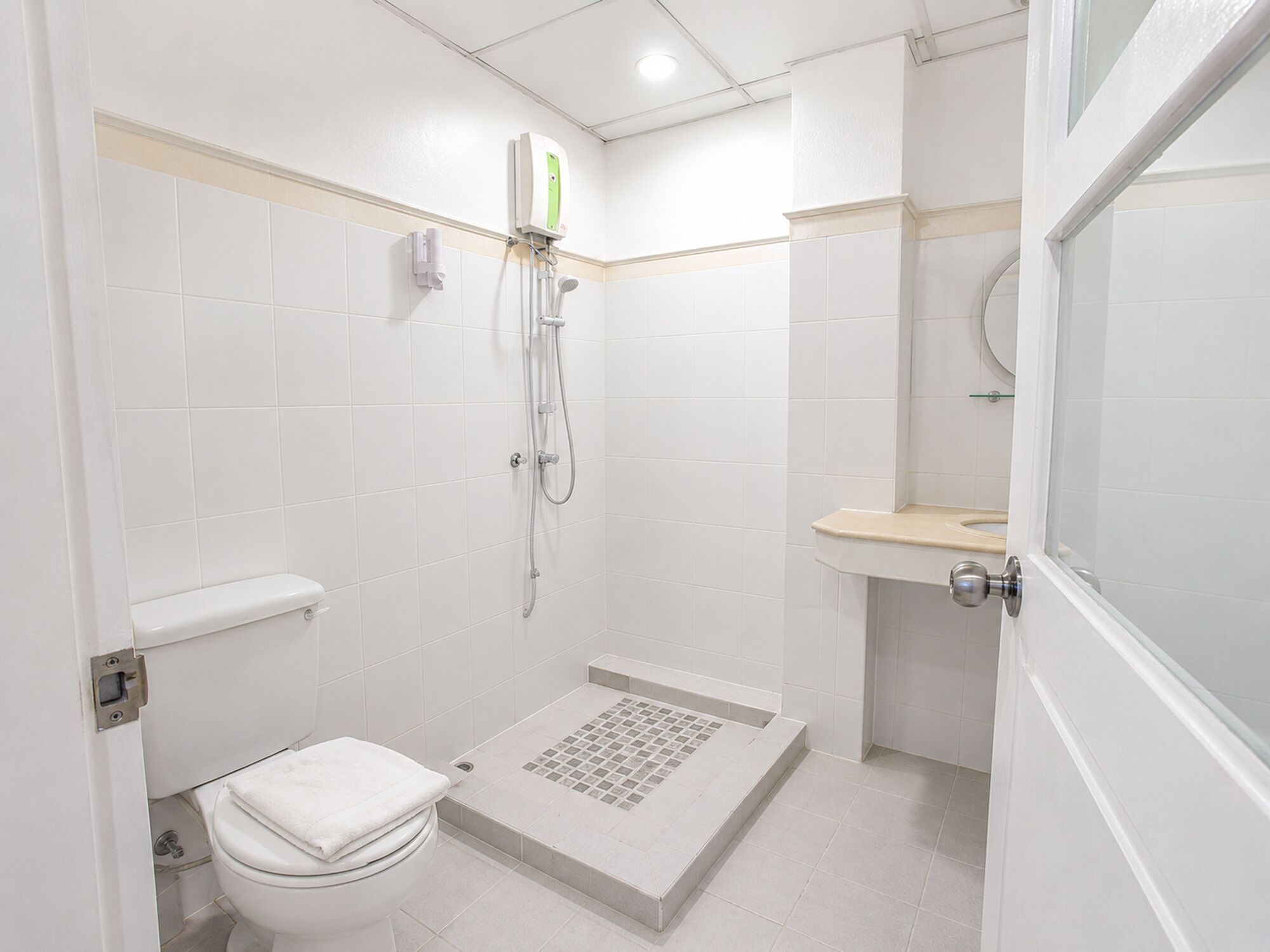 A small, white bathroom with a toilet, shower, and sink.