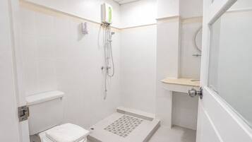A small, white bathroom with a toilet, shower, and sink.