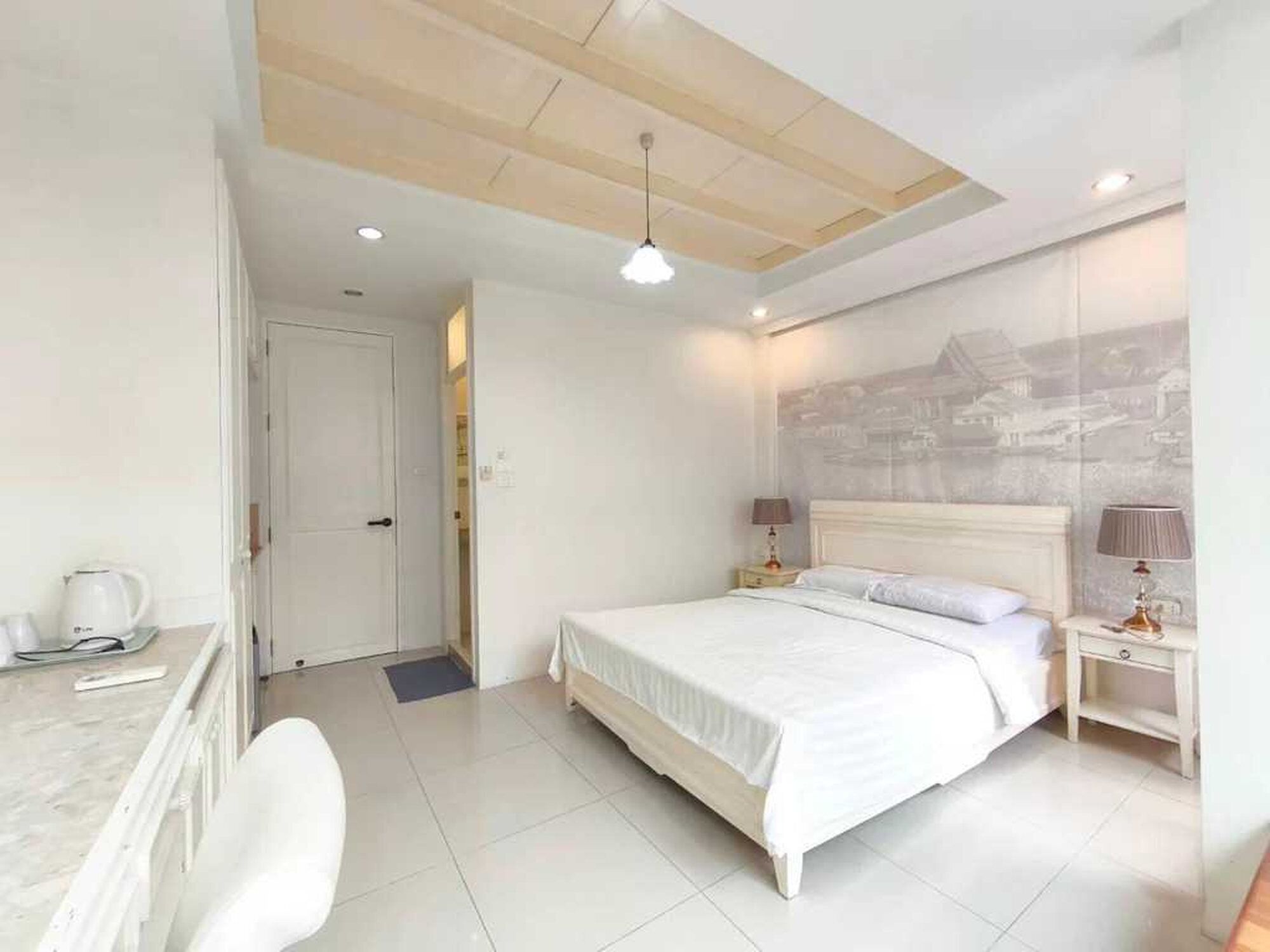 A hotel room with a bed, bedside tables, a desk, a chair, a coffee maker, and a ceiling light.