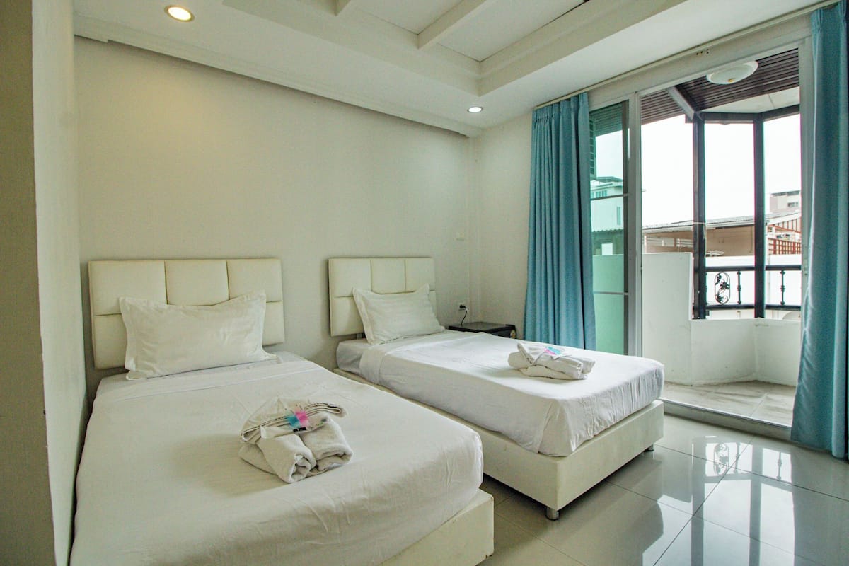 A hotel room with two beds, a nightstand, and a window with curtains.