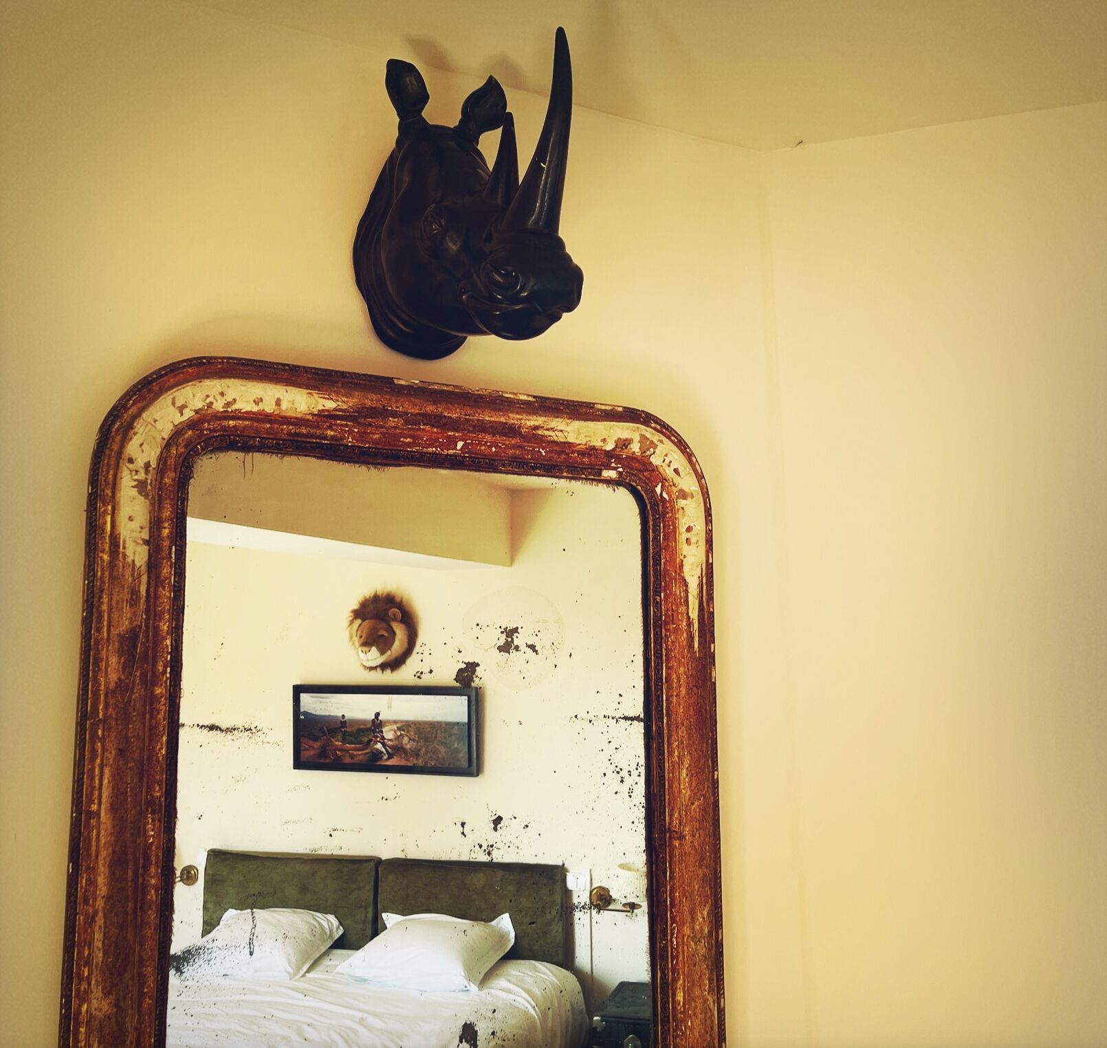 Ein Schlafzimmer mit großem Spiegel, einem Bett, einem Wandbild und einer dekorativen Kopfsulptur.
