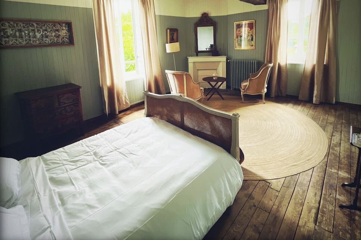 Une chambre à coucher avec un grand lit, un tapis rond, un bureau, une chaise et une cheminée.