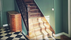 A staircase with wooden steps and black railings, leading to a room with teal walls.