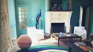 A living room with a fireplace, a peacock statue, and a round rug.