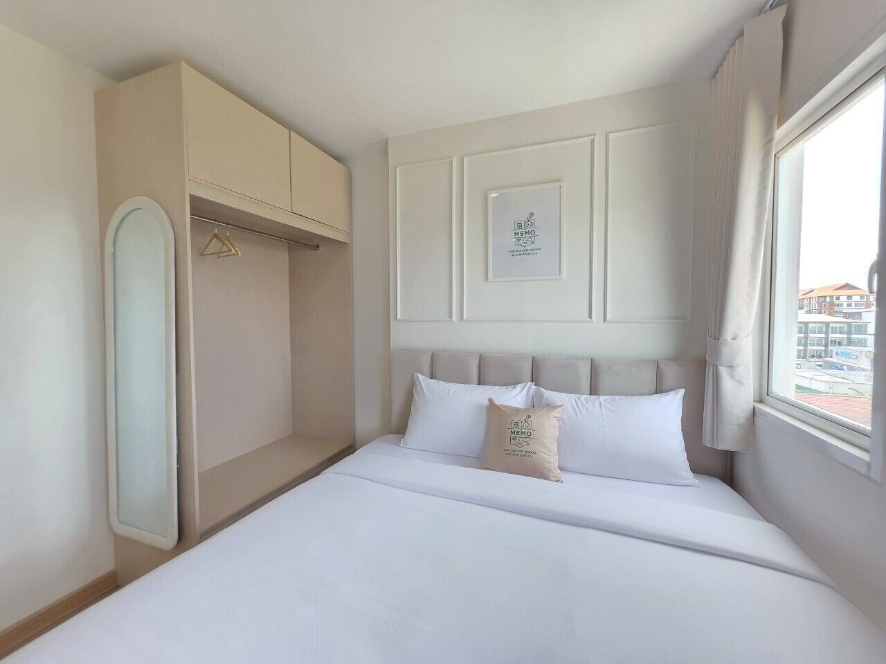 A hotel room with a bed, a wardrobe, and a window with curtains.