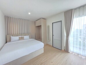 Une chambre d’hôtel avec un grand lit, une armoire, un miroir et une porte.
