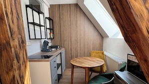 A compact kitchen with a wooden table, a green chair, and a built-in stove. - Vacation apartment Cochem Mosel Pinnerbergstube (Cochem)