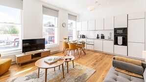 Een moderne woonkamer met een televisie, bank en een eethoek.