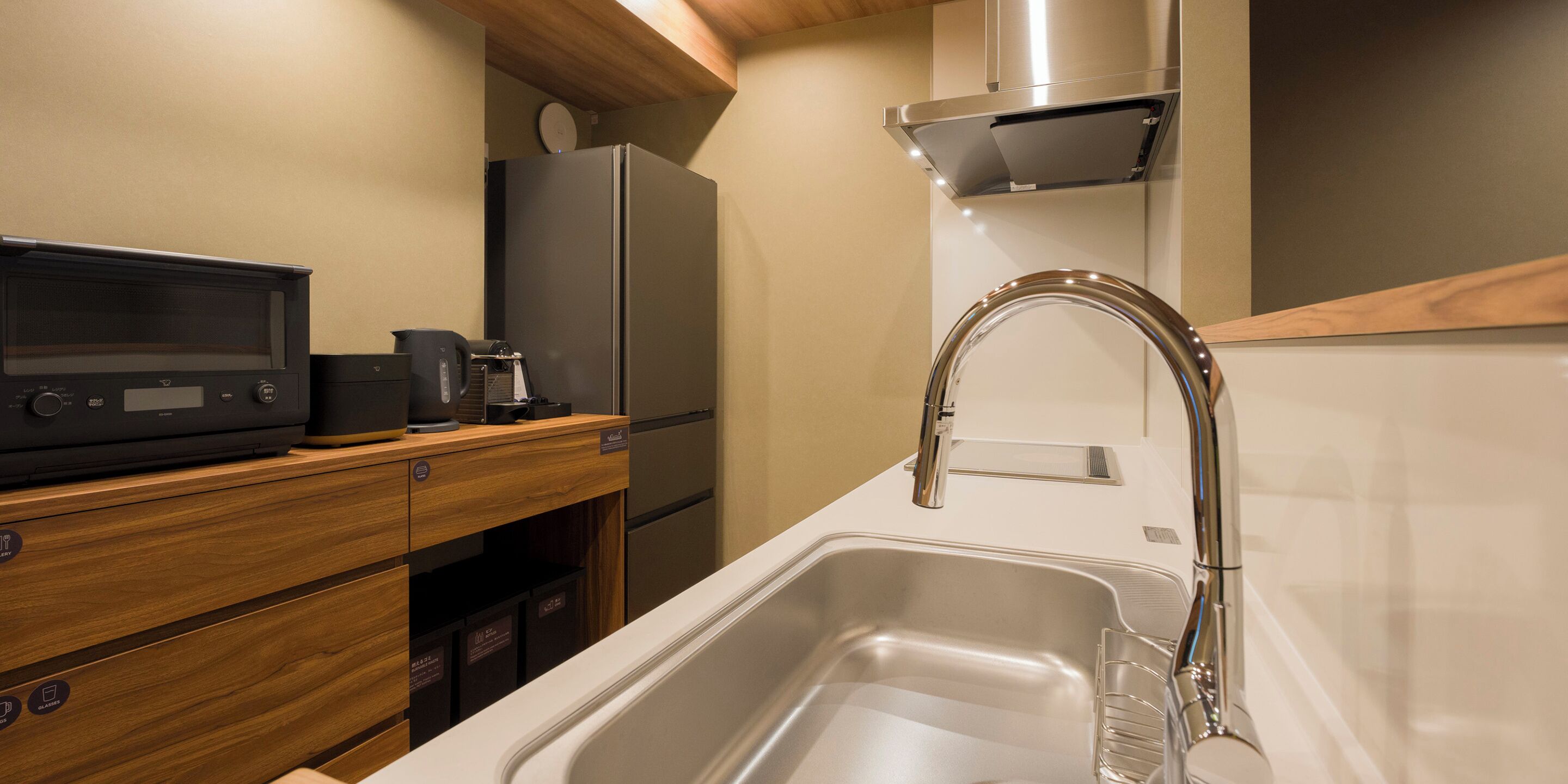 A modern kitchen with a stainless steel sink, a built-in microwave, and a refrigerator.