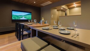 A dining area with a long table set for six, a television screen displaying a landscape, and a mirror on the wall. - Rakuten STAY VILLA Hakone Togendai (Hakone)