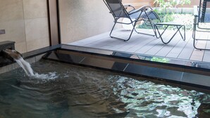 A small indoor water feature with a waterfall, a glass partition, and a patio area with chairs and a table. - Rakuten STAY VILLA Hakone Togendai (Hakone)