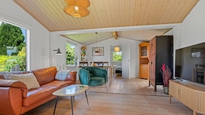 Un vaste espace de vie comprenant un canapé en cuir, un fauteuil vert et un meuble en bois.
