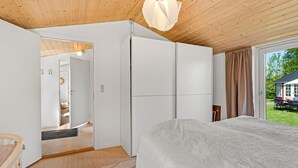 Une chambre à coucher comprenant un lit, une armoire, une porte donnant sur une autre pièce et une vue sur l’extérieur.