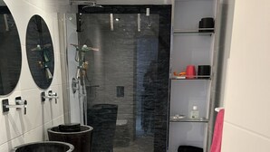 Ein modernes Badezimmer mit Duschkabine aus Glas, einem Waschtisch mit Spiegel und einem Handtuchhalter.